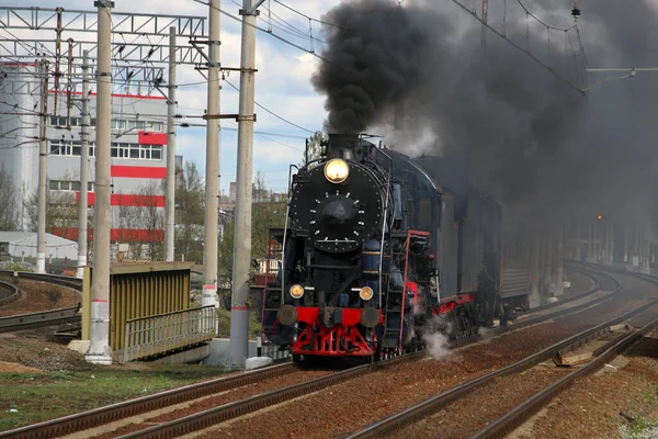 Retro steam train in clouds of smoke riding along the railway rolling tourists