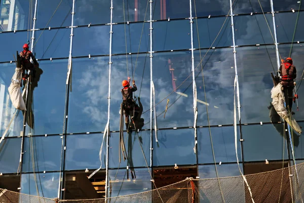 Τρεις Βιομηχανικοί Ορειβάτες Τοποθετούν Γυαλί Παράθυρα Στην Πρόσοψη Ενός Νέου — Φωτογραφία Αρχείου
