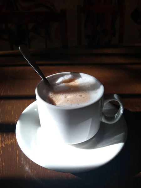 아침에 접시에 찻숟가락이 카푸치노 한잔의 창문에서 아름다운 그림자가 드리워져 — 스톡 사진