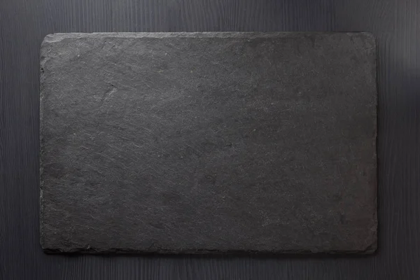 Pedra de ardósia preta em madeira — Fotografia de Stock