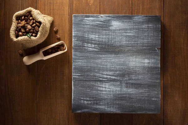 Granos de café en bolsa sobre madera — Foto de Stock