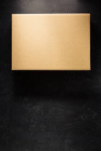 Caixa de papelão sobre fundo preto — Fotografia de Stock