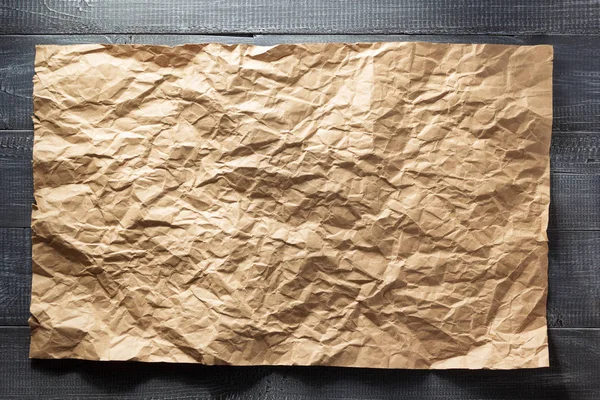 Wrinkled paper at wood — Stock Photo, Image
