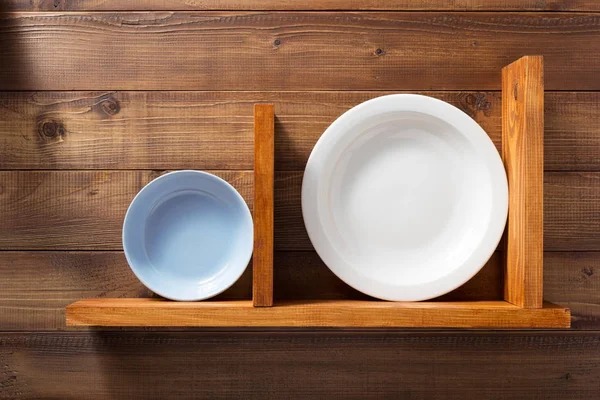 Plate at kitchen wooden shelf at wall — Stock Photo, Image