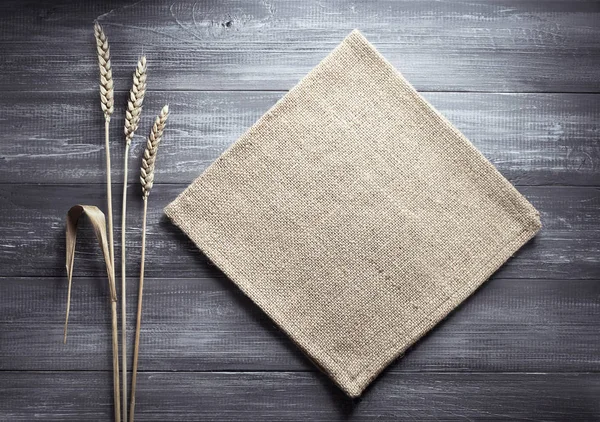 Ears of wheat and cloth on wood — Stock Photo, Image