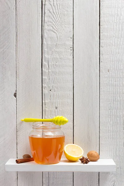 Glass jar of honey on wooden shelf — Stock Photo, Image