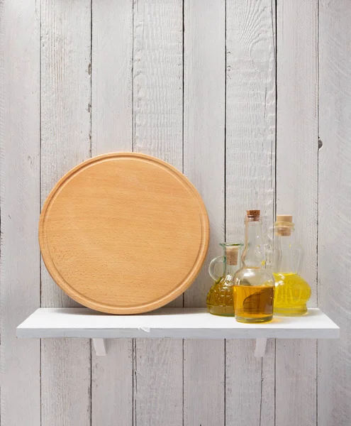 Placa de corte e óleo na prateleira de madeira — Fotografia de Stock