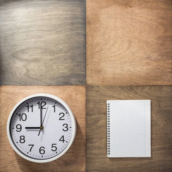 Notebook a nástěnné hodiny v dřevěné pozadí — Stock fotografie
