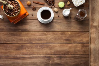 Tahta arka planda bir fincan kahve ve fasulye.