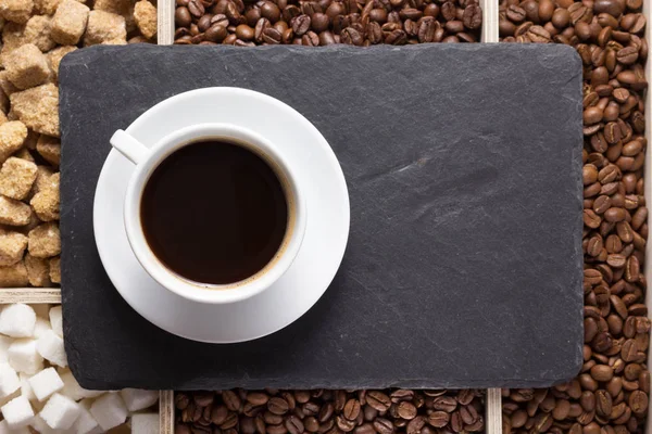 Tasse de café et haricots sur plateau noir en pierre d'ardoise — Photo