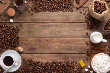 Tahta arka planda bir fincan kahve ve fasulye.