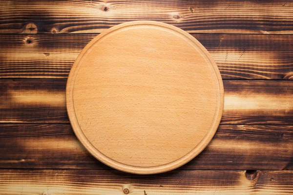 Доска для резки пиццы на деревенском деревянном фоне — стоковое фото