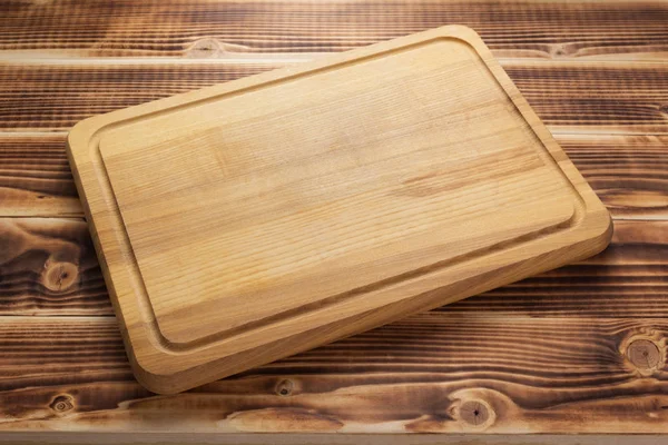 Cutting board at rustic wooden plank background — Stock Photo, Image