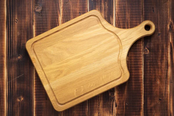 Cutting board at rustic wooden plank background — Stock Photo, Image