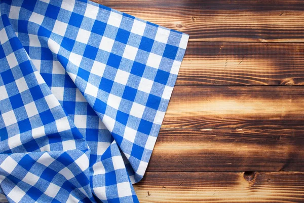 checked cloth napkin or tablecloth at rustic wooden plank board table background, top view