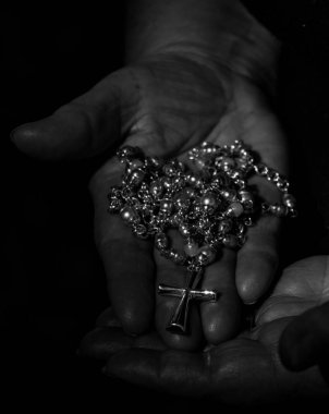 Bir kadın bir haç ile siyah ve beyaz tespih eller