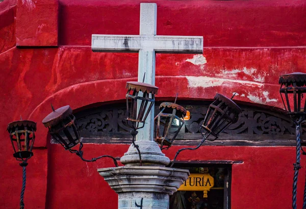 Old cross with metal streetlights with red background