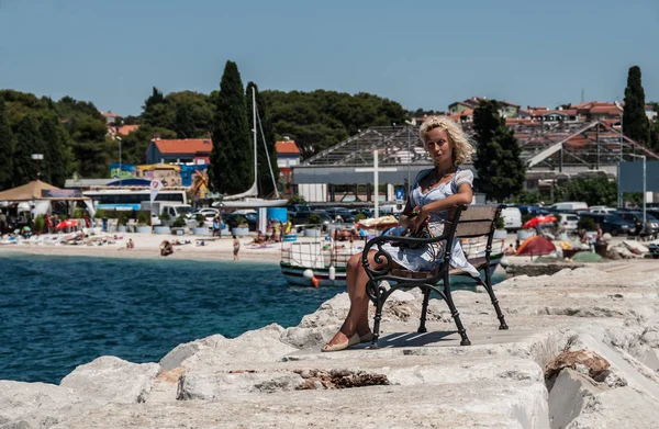 Молодая европейская блондинка сидит на скамейке у Средиземного моря . — стоковое фото