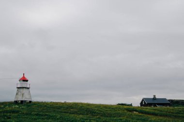 Deniz feneri ve ev bulutlar arka planda ve çim Kuzey Norveç'te