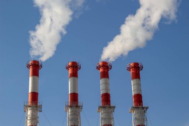 Isı ve elektrik santrali, açık mavi gökyüzüne karşı pipo kirliliği.