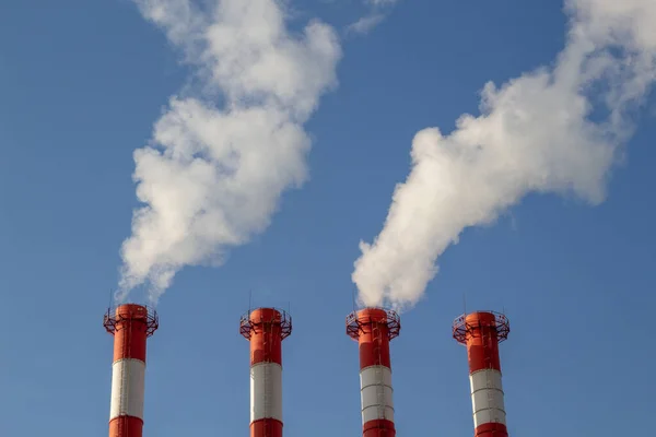 Isı ve elektrik santrali, açık mavi gökyüzüne karşı pipo kirliliği.