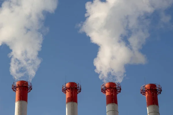 Isı ve elektrik santrali, açık mavi gökyüzüne karşı pipo kirliliği.