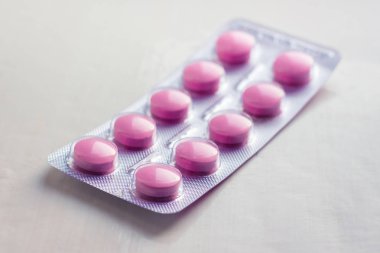 blister with pills of pink color on a white background_