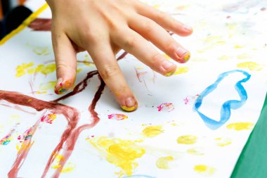 The child performs a drawing on paper with his fingers_
