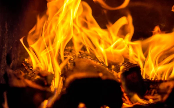 В камине ярко горит горячий красный огонь на темном бэкгро — стоковое фото