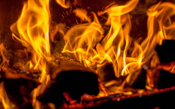 В камине ярко горит горячий красный огонь на темном бэкгро — стоковое фото