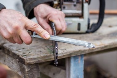 bir törpülemek onun elinde olan bir adam bir elektrikli testere zinciri keskinleştirir prepar