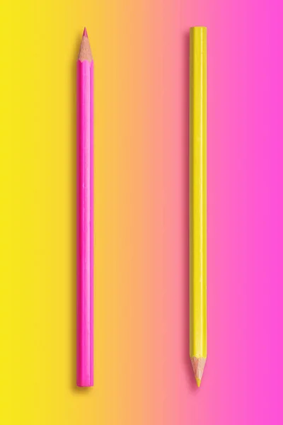 Два олівці жовтий і рожевий, градієнтний фон від жовтого до — стокове фото