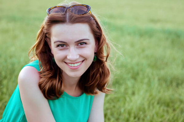 portrait of young girl against  background of green grass, an op