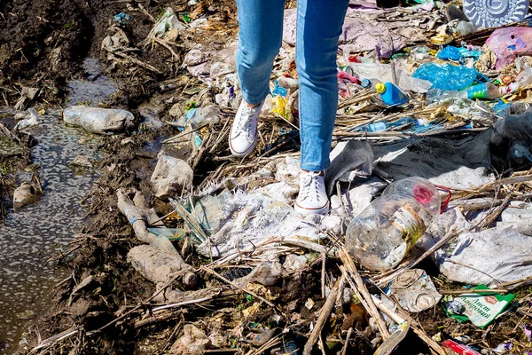 Pile of garbage under  feet of girl. Environmental pollution. Ec