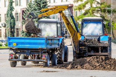 Excavator loads the earth on the tractor trailer_