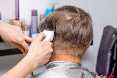 Hairdresser makes  stylish hairstyle for an elderly man_