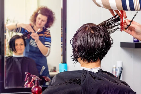 Mulher no salão de beleza muda sua imagem. Cabeleireiro faz cabelo — Fotografia de Stock