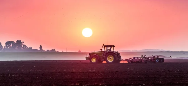 Il trattore al mattino durante l'alba elabora il terreno — Foto Stock