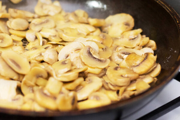 On a frying pan fried mushrooms. Preparation of champignons in t