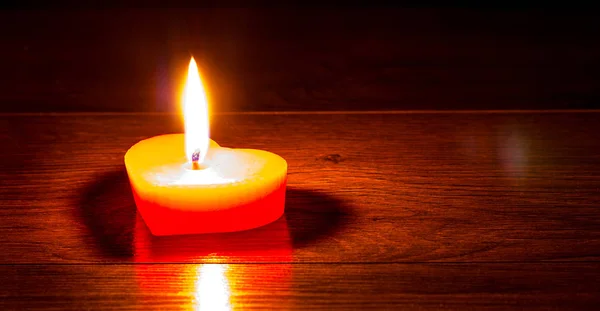 Червона свічка у вигляді серця на темному дерев'яному фоні. Ф'юрі — стокове фото