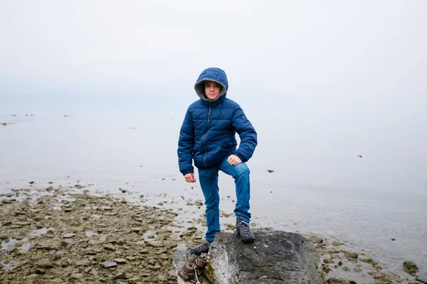 Portret van een kind in de winter aan het meer met mist en wolken — Stockfoto