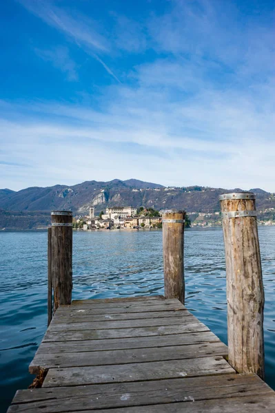 Orta Gölü 'ndeki ahşap rıhtım, San Giulio adasının karşısında Benedictine rahibelerinden oluşan bir manastır, ilkbaharda sakin ve mavi bir göl.