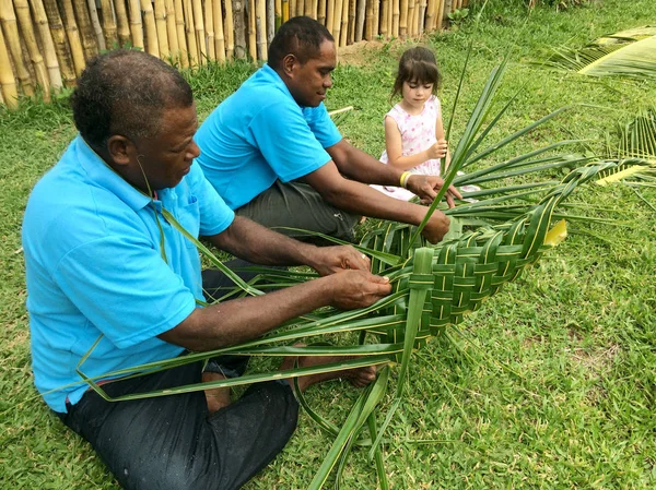 Fijian men teach young tourist girl how to create a basket from — Stock Photo, Image