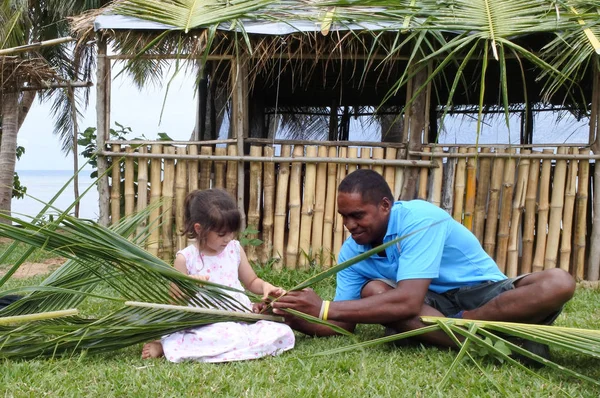 Indigenous Fijian man teach young tourist girl how to create a b