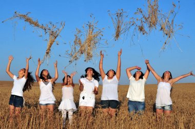 Happy young Israeli women throwing wheat to the air on Shavuot J clipart