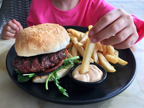 Young girl eat a big hamburger with chips — Stock Photo, Image