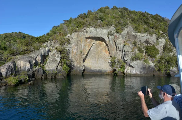 Visitantes fotografiando la icónica escultura rupestre maorí en el lago Tau —  Fotos de Stock