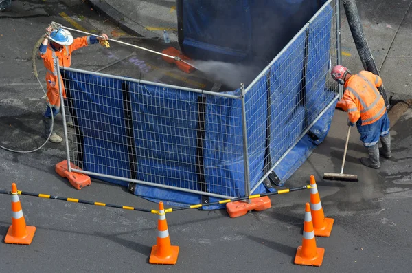 Дорожні працівники прибирають каналізацію на міській вулиці — стокове фото