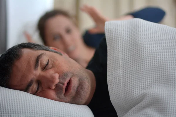 Mujer sufre de su pareja masculina roncando en la cama — Foto de Stock