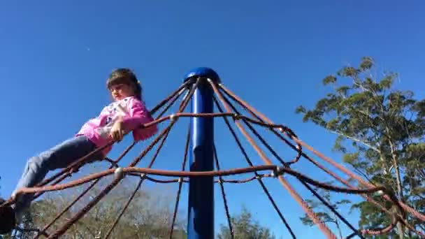Meisje speelt op een merry-go-round op een speelplaats — Stockvideo